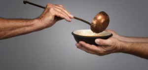 man holding a bowl in both hands, receiving a serving of soup from another man holding a soup ladle